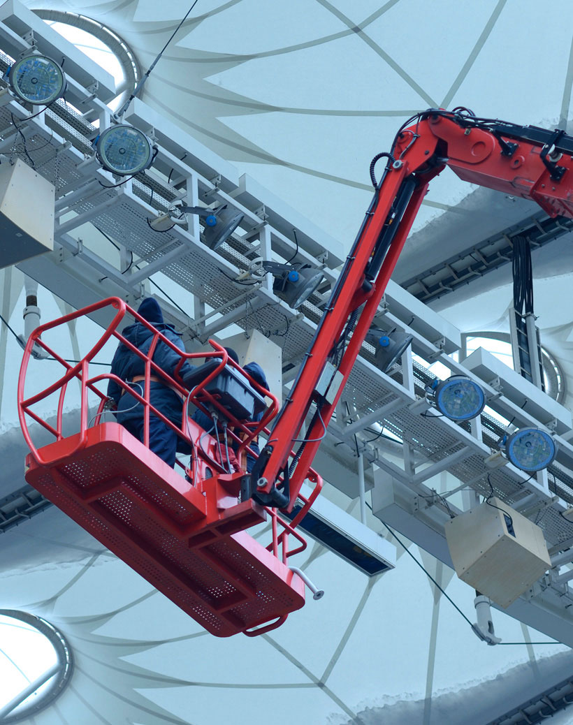 Workers on a lift inspecting stadium roof equipment